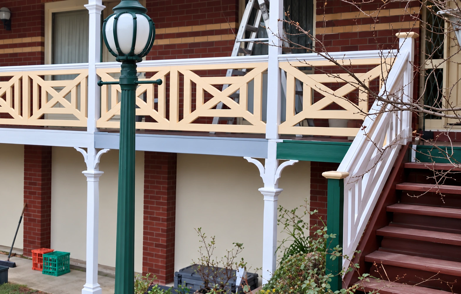 Cream cross-panel timber balustrades on a red-brick verandah beside an external staircase